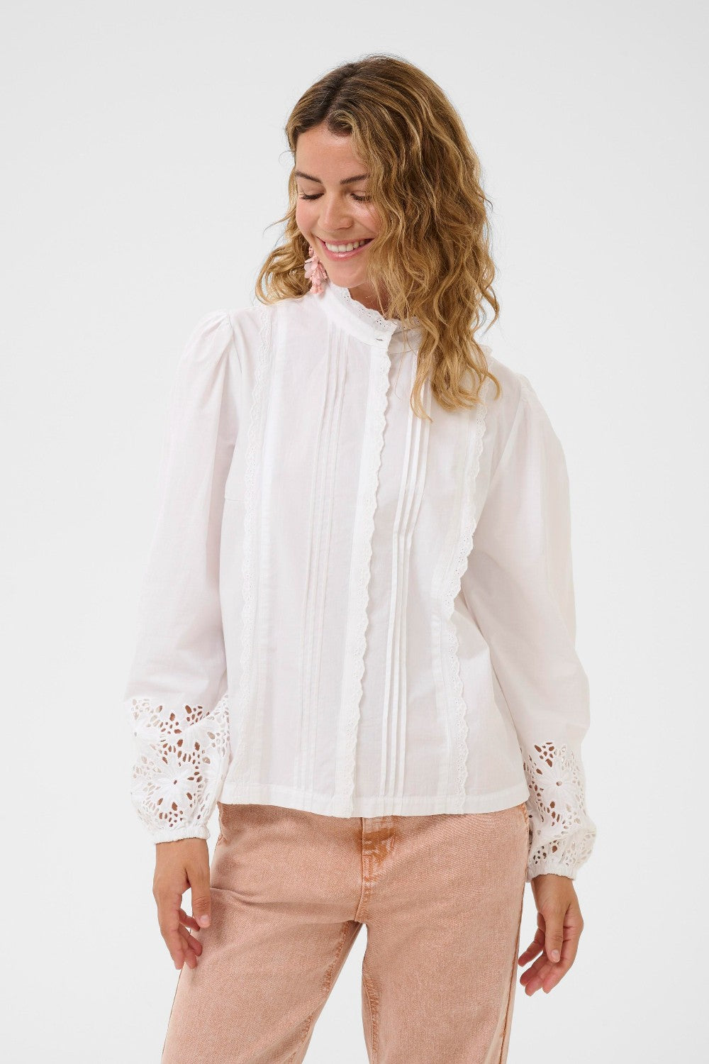 Woman wearing a white blouse with lace details on a white background
