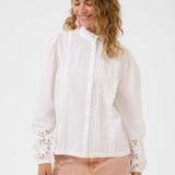 Woman wearing a white blouse with lace details on a white background