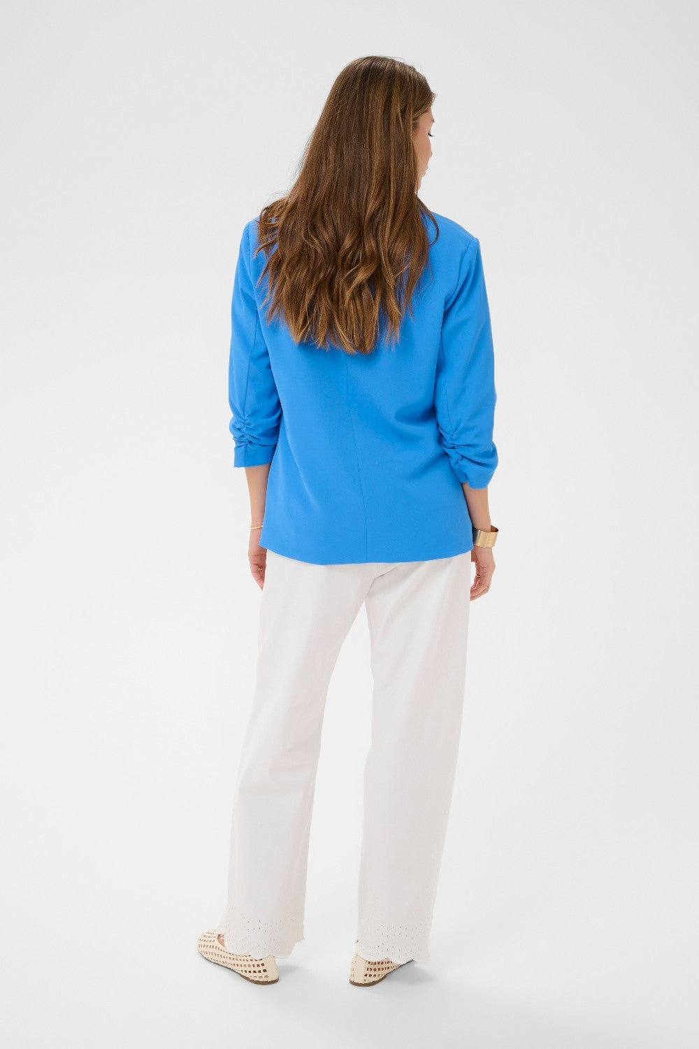 Woman wearing a blue blazer and white pants on a white background