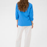 Woman wearing a blue blazer and white pants on a white background