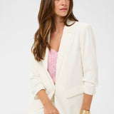 Woman wearing a white blazer over a pink top on a white background