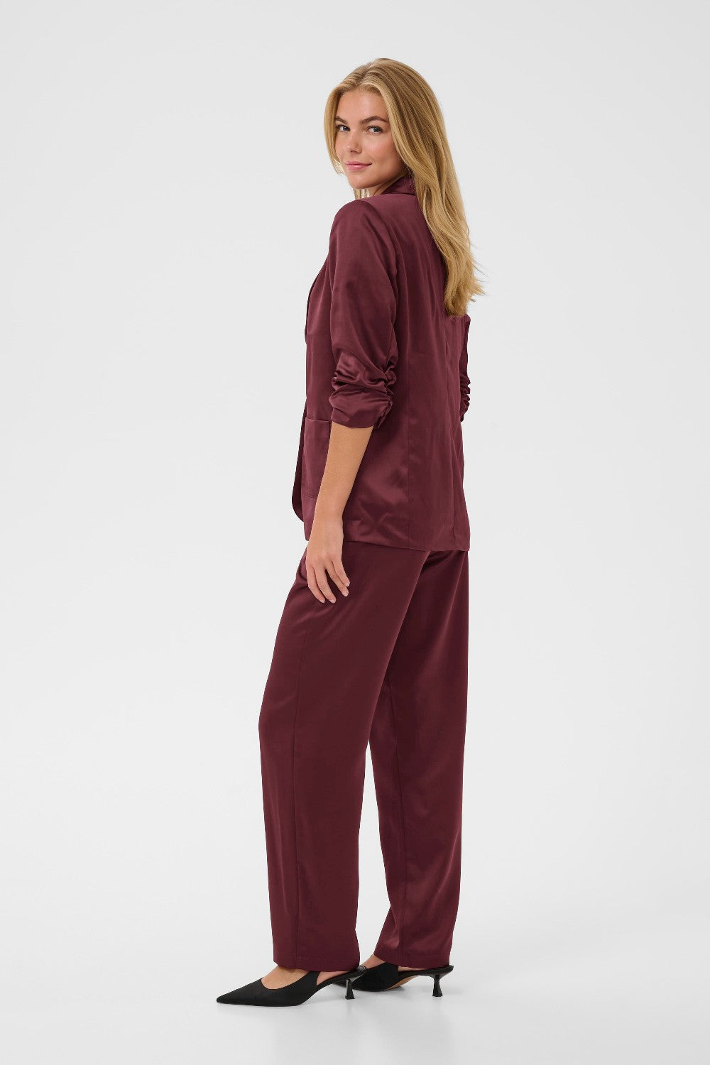 Woman wearing a burgundy satin outfit on a white background