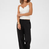 Woman wearing a white top and black pants on a white background