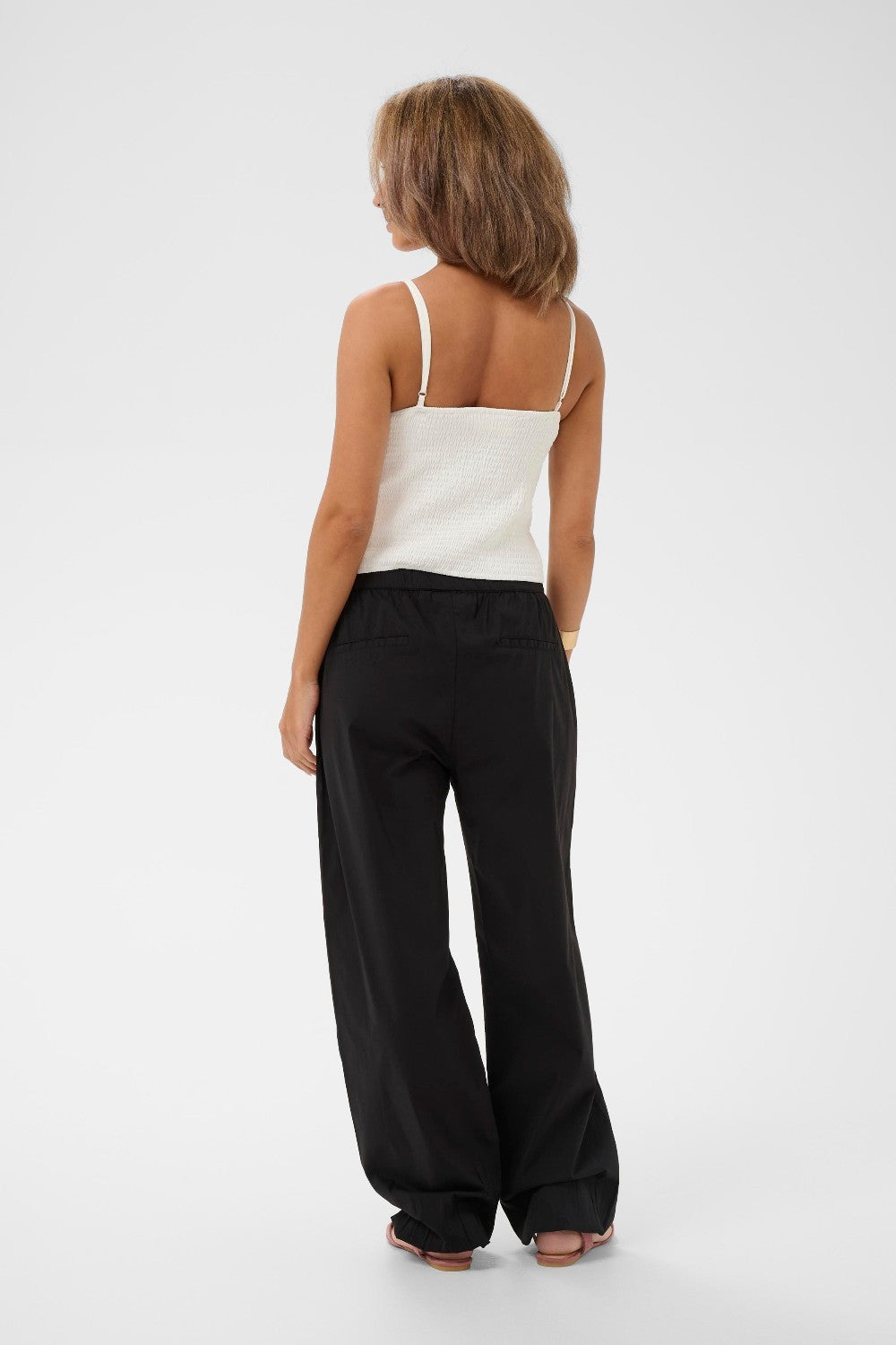 Woman wearing a white top and black pants on a white background