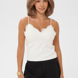 Woman wearing a white lace top and black pants on a white background