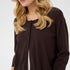 Woman wearing a brown button-up cardigan with beige pants on a white background