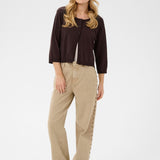 Woman wearing a brown cardigan and beige pants on a white background