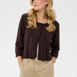 Woman wearing a brown button-up cardigan and beige pants on a white background