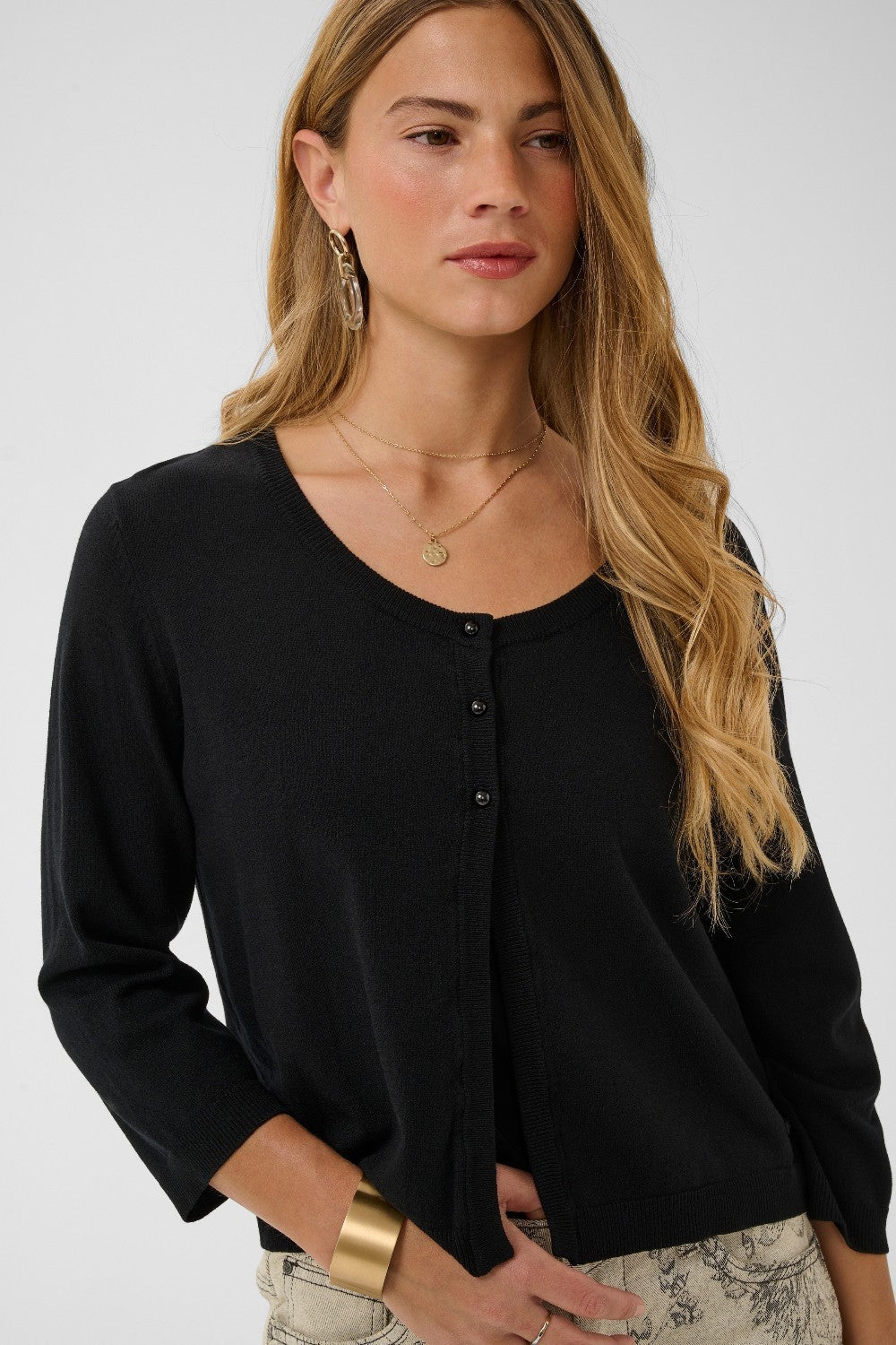 Woman wearing a black cardigan with a plain background
