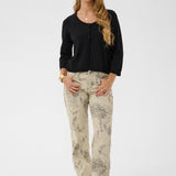 Woman wearing a black cardigan and patterned pants on a white background