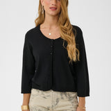 Woman wearing a black cardigan and patterned pants on a white background