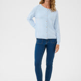 Woman wearing a light blue cardigan and dark blue jeans on a white background