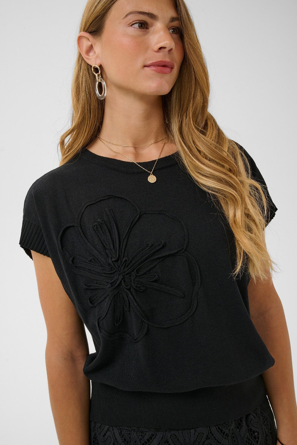 Woman wearing a black top with a floral design on a white background