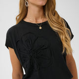 Woman wearing a black top with a floral design on a white background