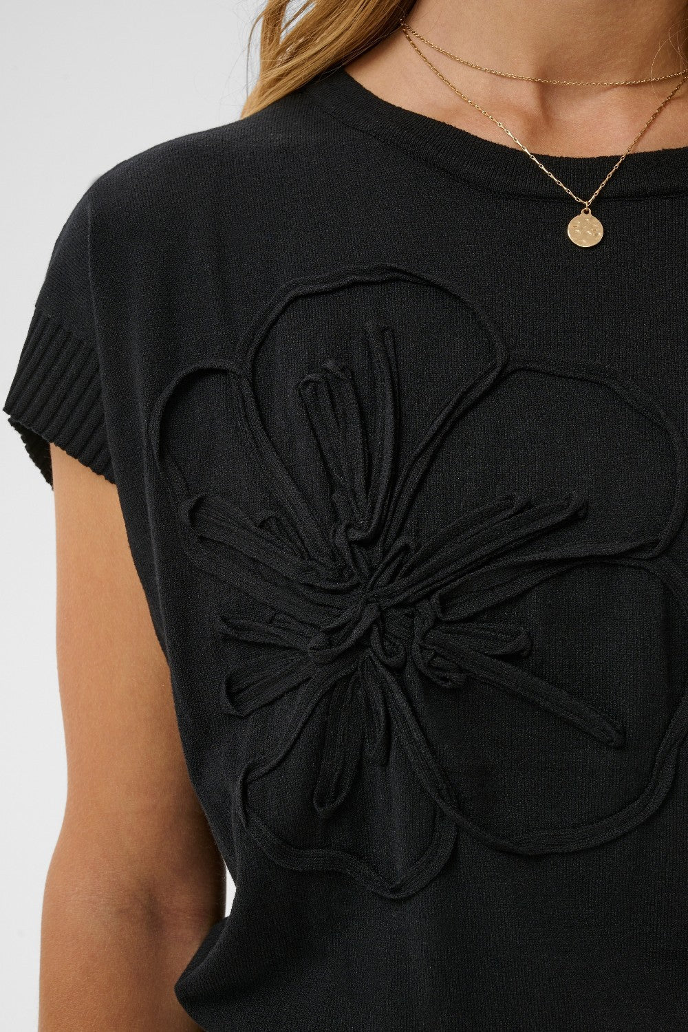Black t-shirt with floral design on a plain background
