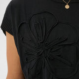 Black t-shirt with floral design on a plain background