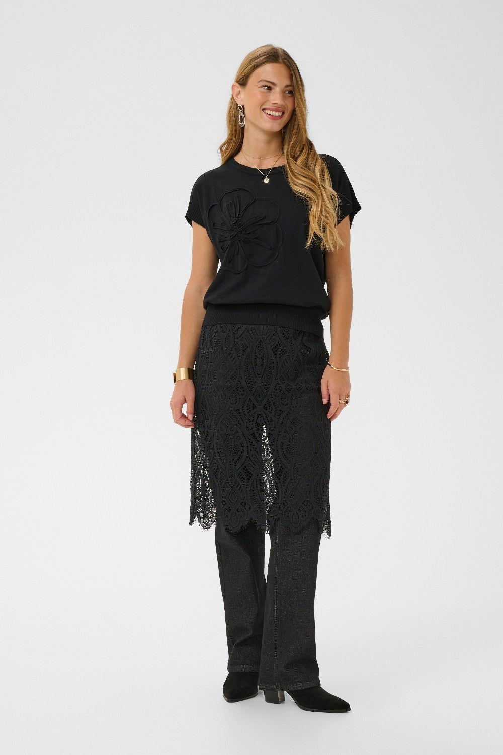 Woman wearing a black outfit with a lace skirt on a white background
