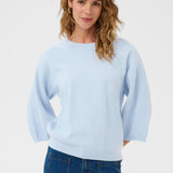 Woman wearing a light blue sweater and blue jeans on a white background