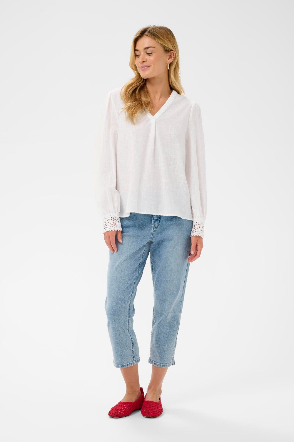 Woman wearing a white blouse and light blue jeans on a white background
