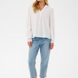 Woman wearing a white blouse and light blue jeans on a white background