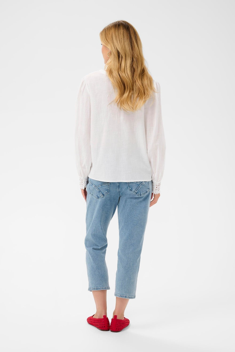 Person wearing a white shirt and light blue jeans on a white background