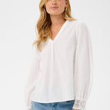 Woman wearing a white blouse with lace cuffs and trim on a white background