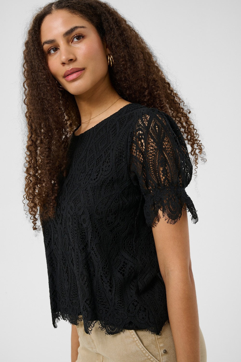 Woman wearing a black lace top against a white background