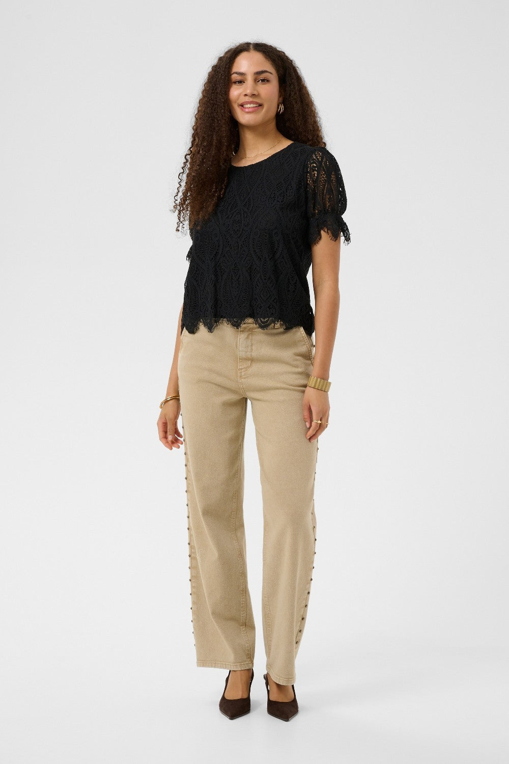 Woman wearing a black top and beige pants on a white background
