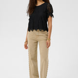 Woman wearing a black top and beige pants on a white background