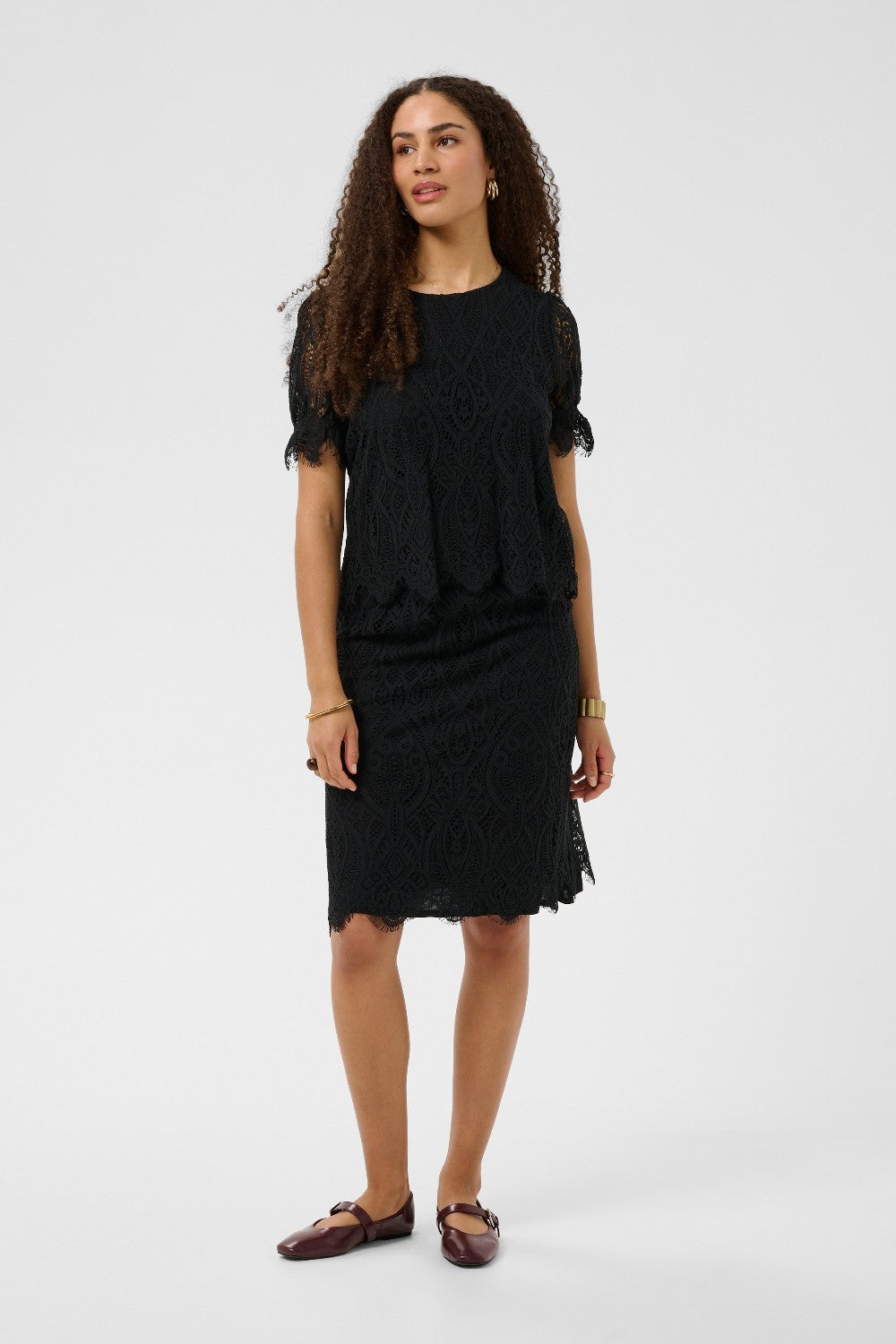 Woman wearing a black outfit with ruffled sleeves on a white background