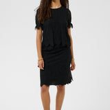 Woman wearing a black outfit with ruffled sleeves on a white background