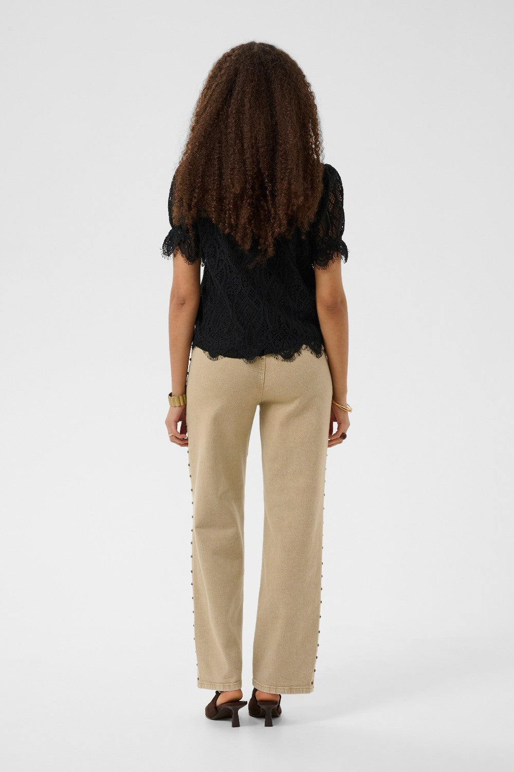 Person wearing a black top and beige pants on a white background