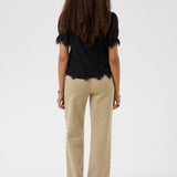 Person wearing a black top and beige pants on a white background