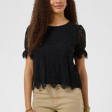 Woman wearing a black lace top and beige pants on a white background