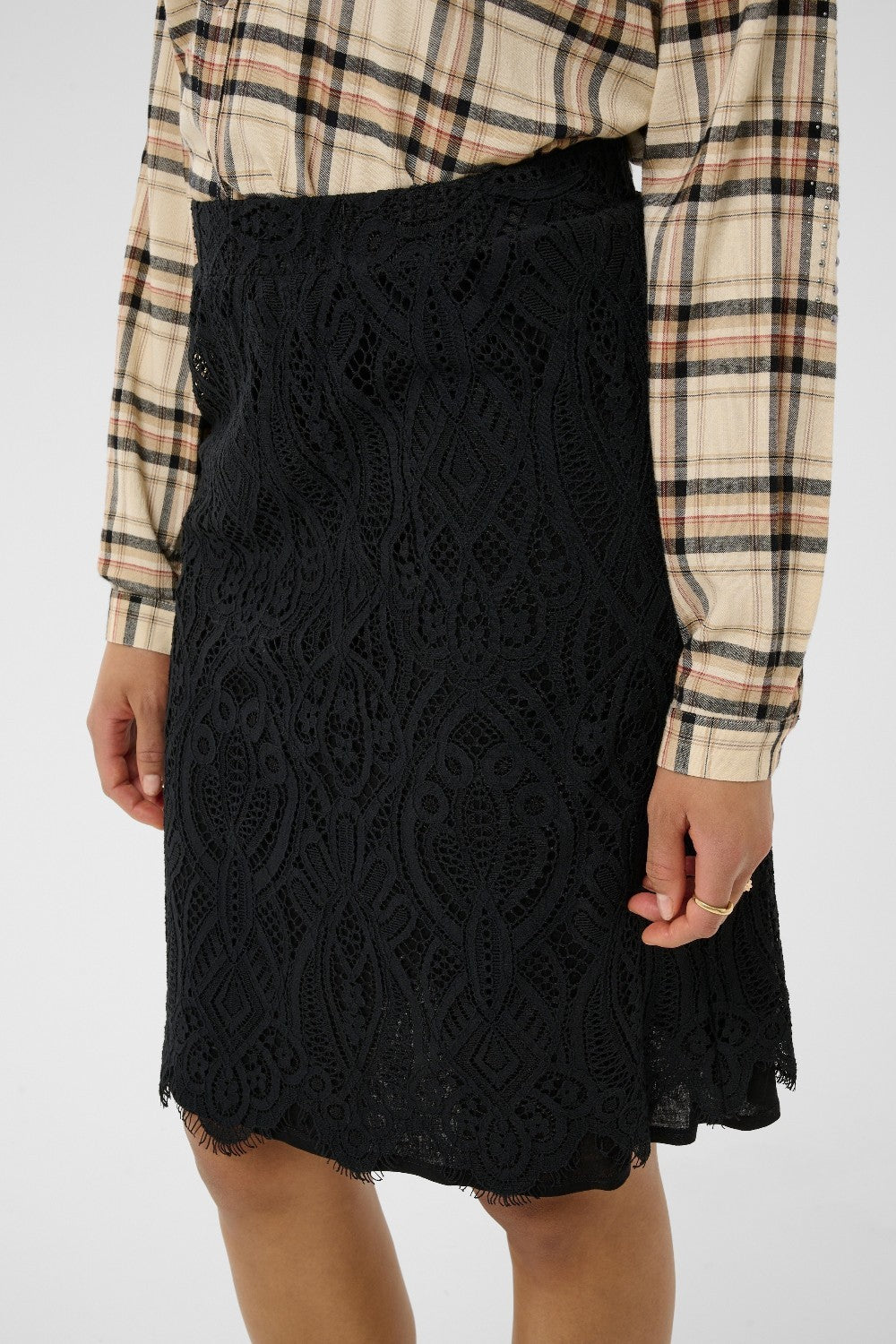 Black lace skirt worn with a plaid shirt on a white background