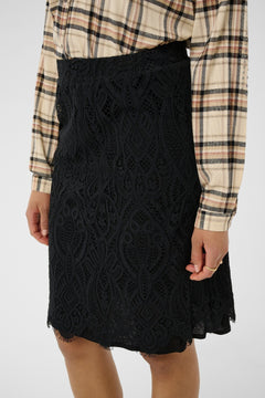 Black lace skirt worn with a plaid shirt on a white background