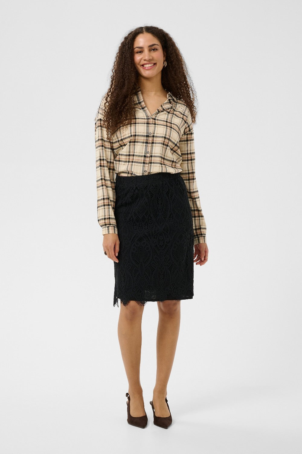 Woman wearing a plaid shirt and black skirt on a white background