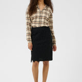 Woman wearing a plaid shirt and black skirt on a white background