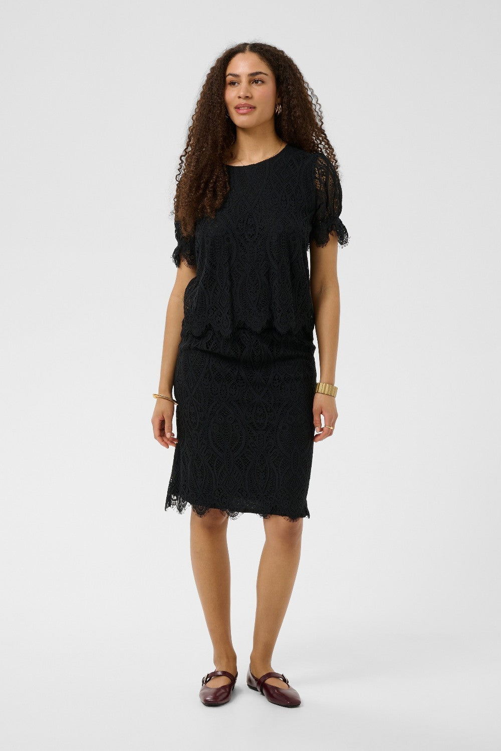 Woman wearing a black lace top and skirt on a white background