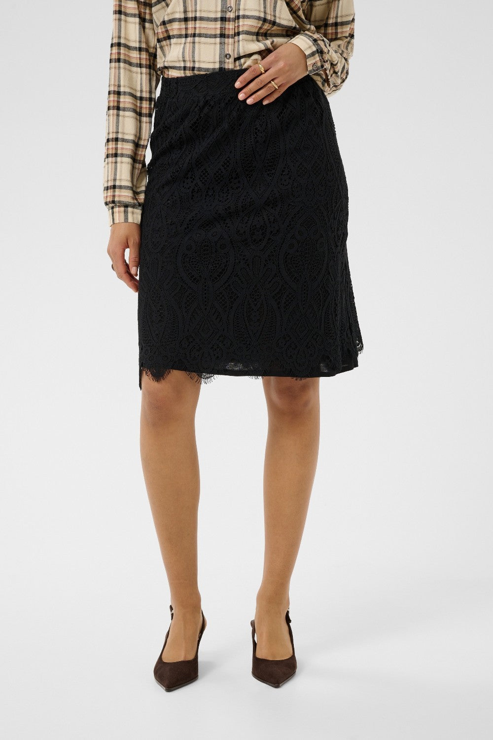 Person wearing a black skirt with a plaid shirt on a white background