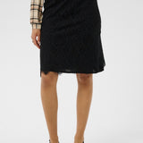 Person wearing a black skirt with a plaid shirt on a white background