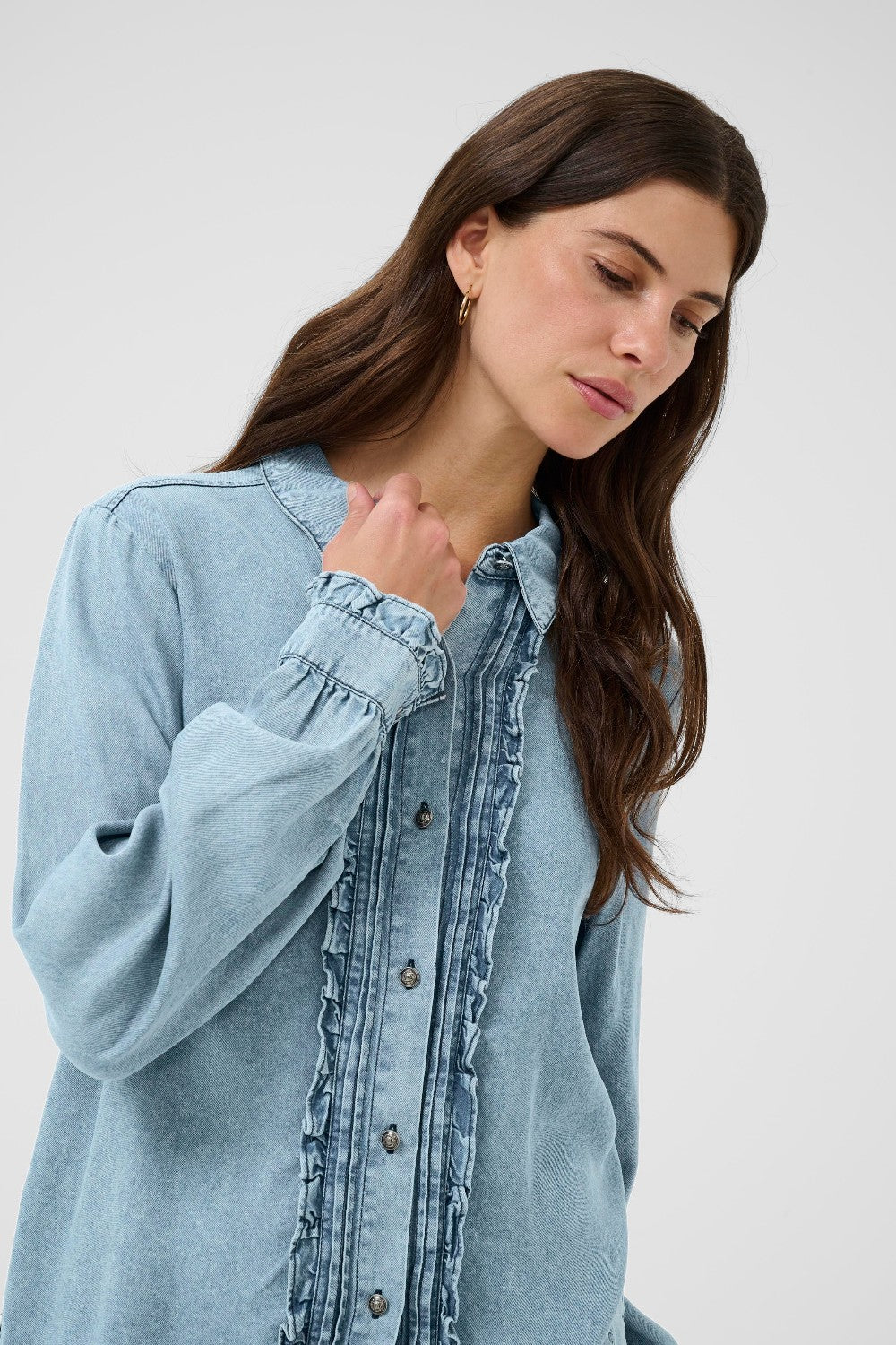 Woman wearing a light blue denim shirt against a white background