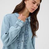 Woman wearing a light blue denim shirt against a white background