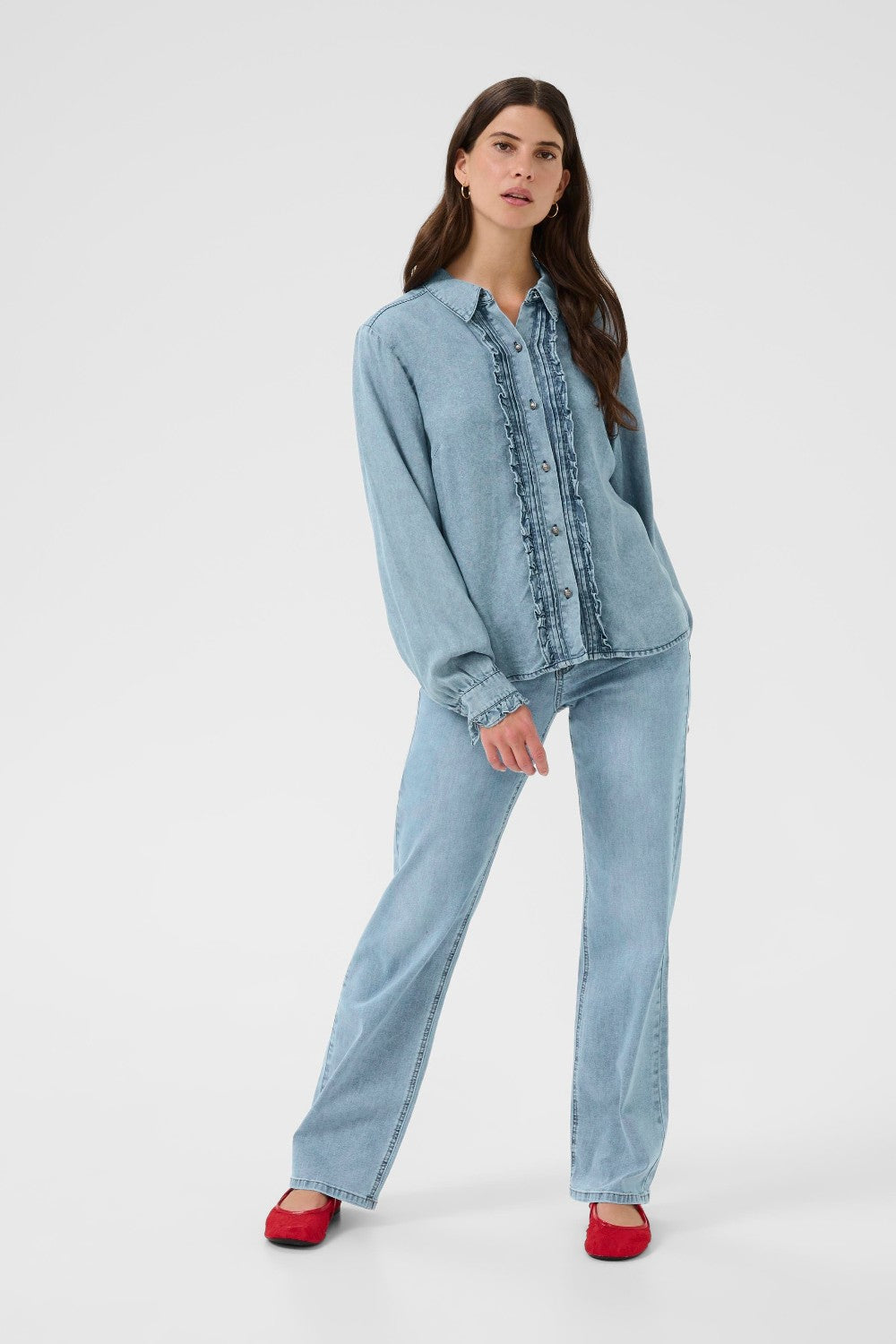 Woman wearing a light blue denim outfit on a white background