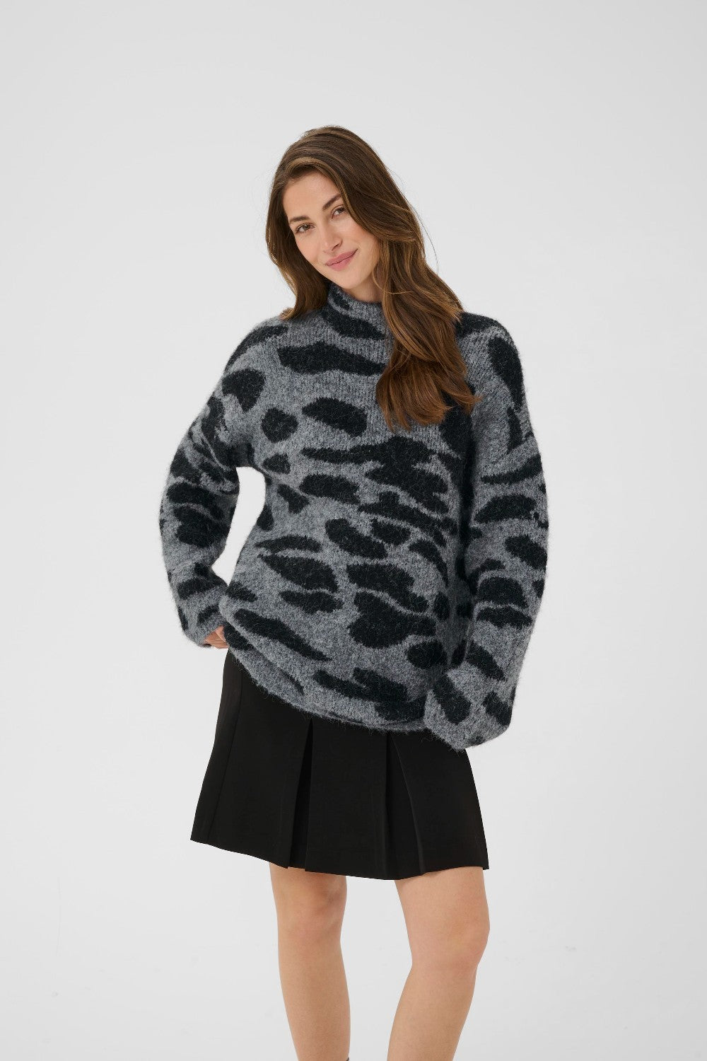 Woman wearing a gray leopard print sweater and black skirt on a white background