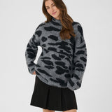 Woman wearing a gray leopard print sweater and black skirt on a white background