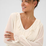 Woman wearing a white draped garment against a plain background