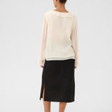 Person wearing a white top and black skirt on a white background