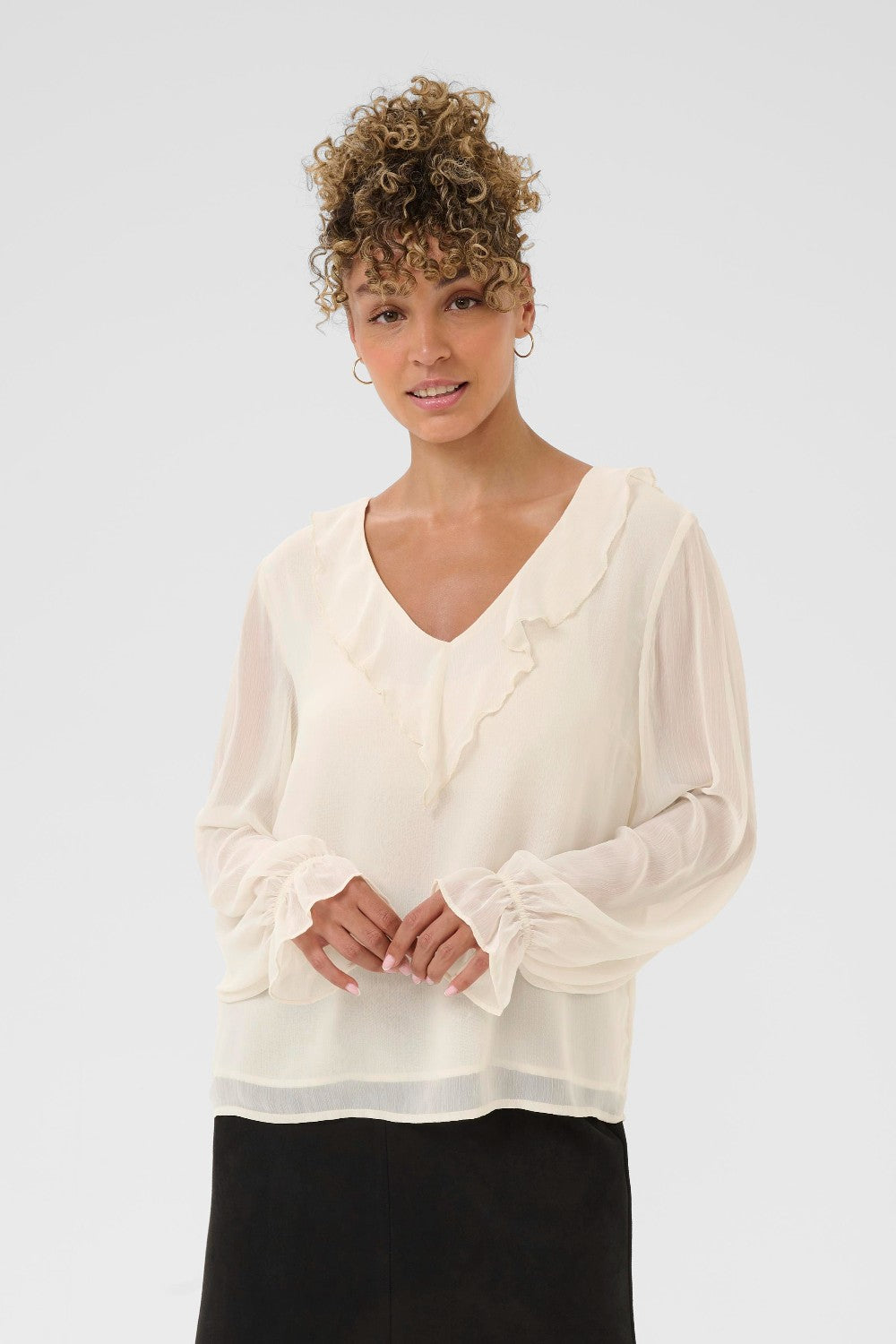 Woman wearing a white blouse with long sleeves on a plain background