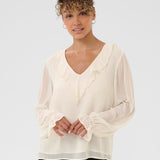Woman wearing a white blouse with long sleeves on a plain background